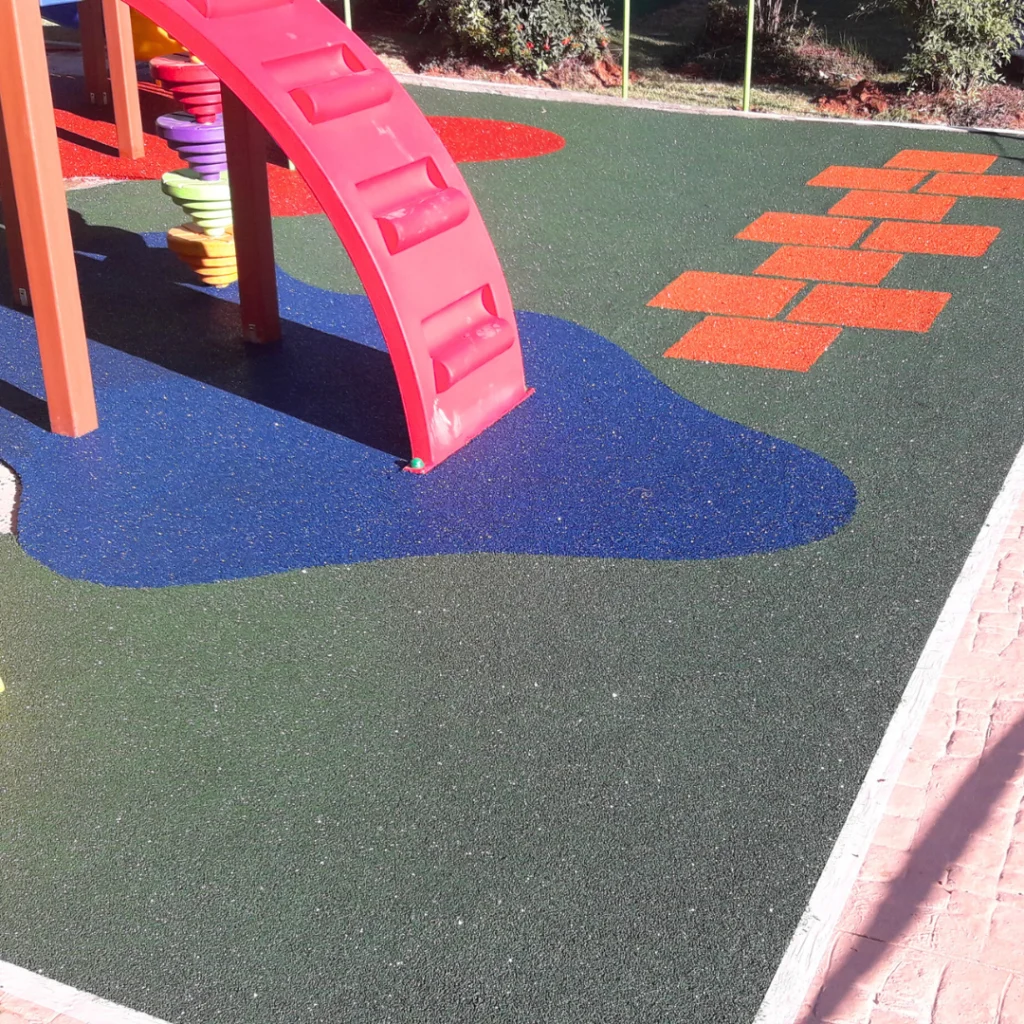 Piso contínuo aplicado em Playground colorido com escorregador, balanços e brinquedos para crianças se divertirem.