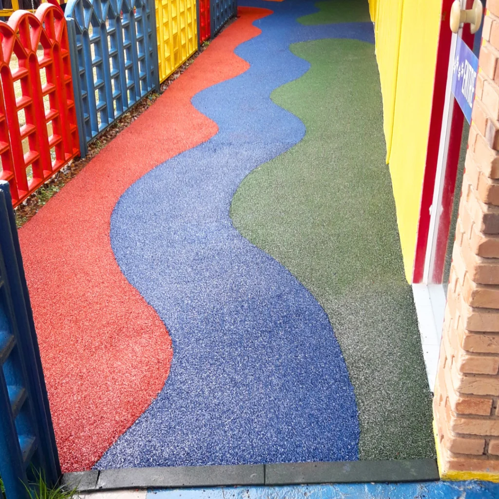 Piso contínuo aplicado em Playground com Paginação de Jogo Amarelinha com Blocos na cor Amarela e Números na cor Terracota em chão na cor Terracota com detalhes em Azul.