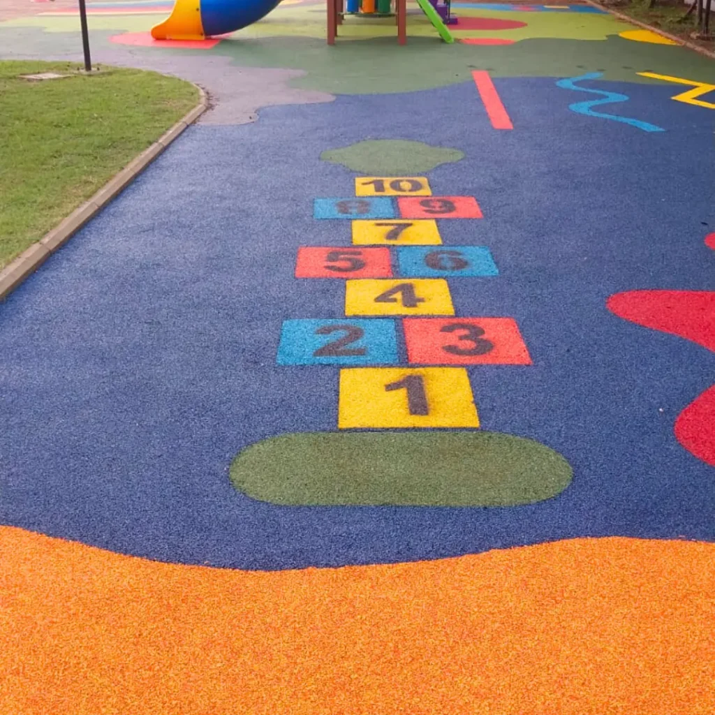 Playground com Paginação de Jogo Amarelinha com Blocos na cor Amarela, Azul, Rosa Salmão e Números na cor Preta.